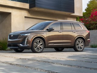 A brown Cadillac XT6 parked by a house
